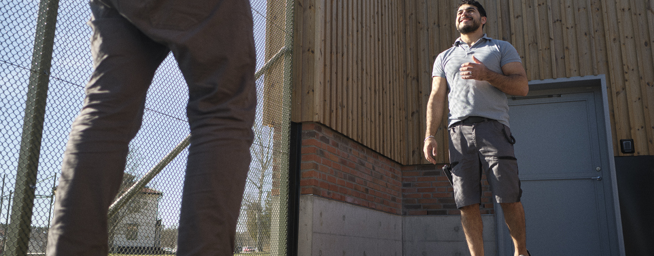  En medarbetare och en ungdom ute på gården, solen skiner och himlen syns i bakgrunden.