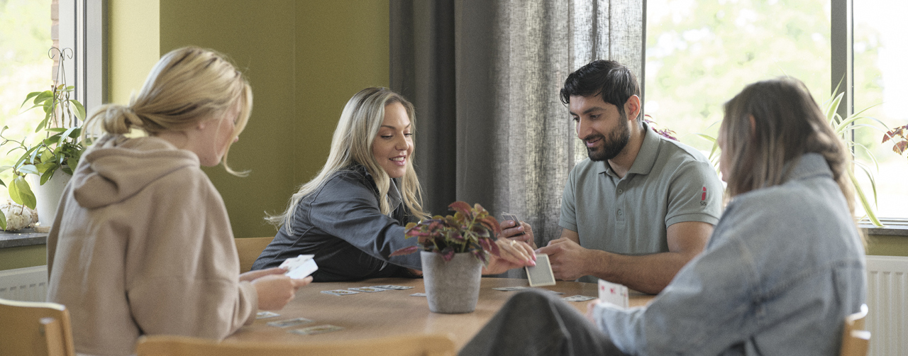 Medarbetare runt ett bord med ungdomar.