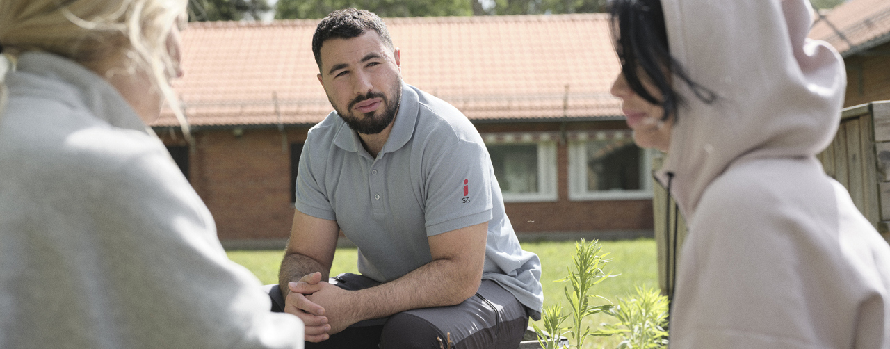 En medarbetare och två ungdomar utomhus